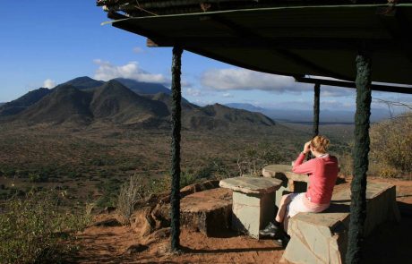 Frau mit Fernglas blickt in die den Samburu Nationalpark in Kenia