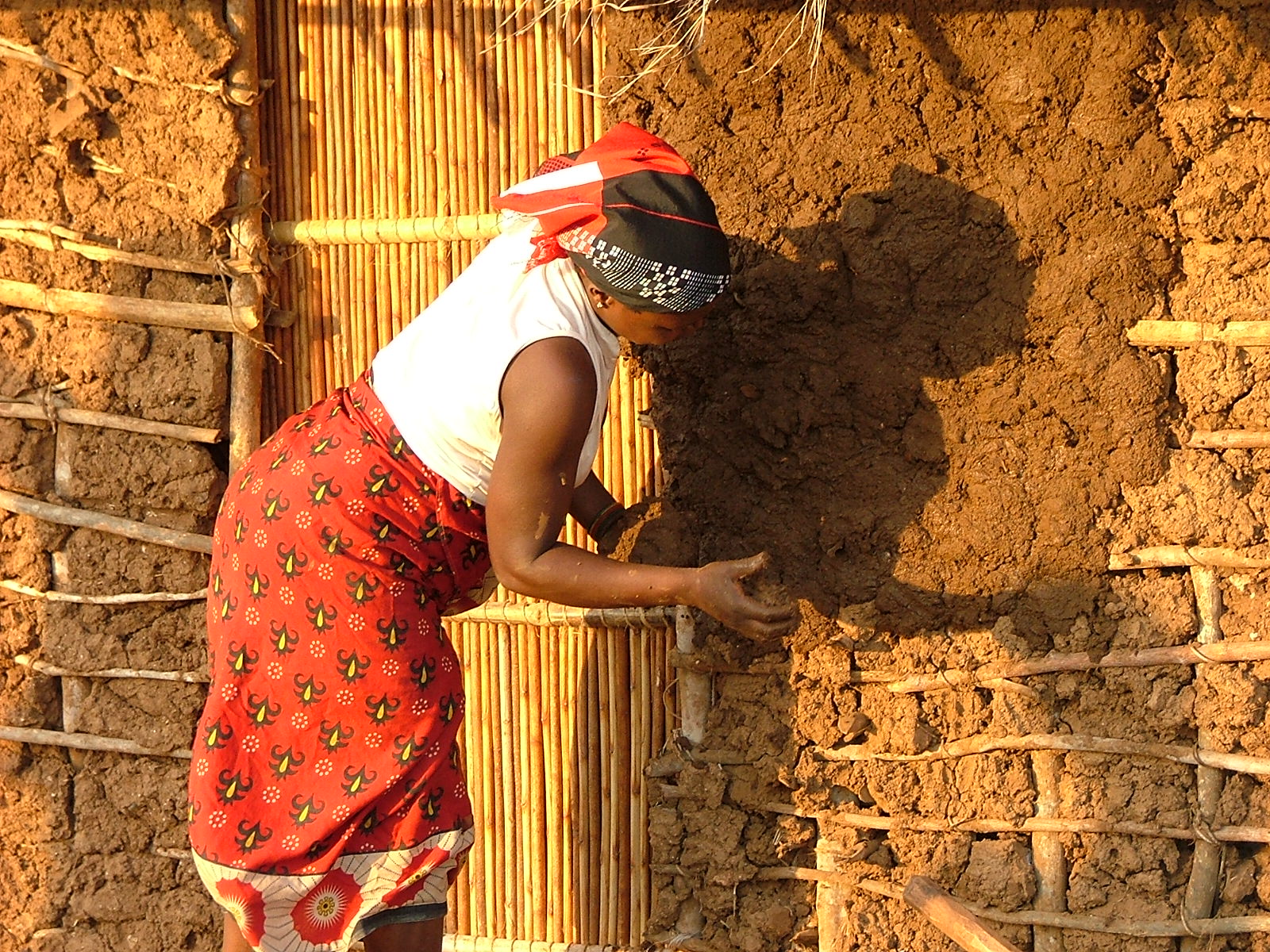 Frau repariert eine Hütte mit getrocknetem Dung