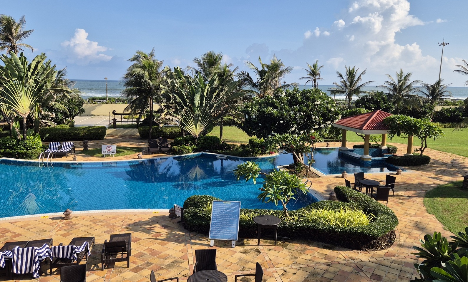 Poolanlage mit Palmen und Meeresblick des Hans Coco Resorts in Puri