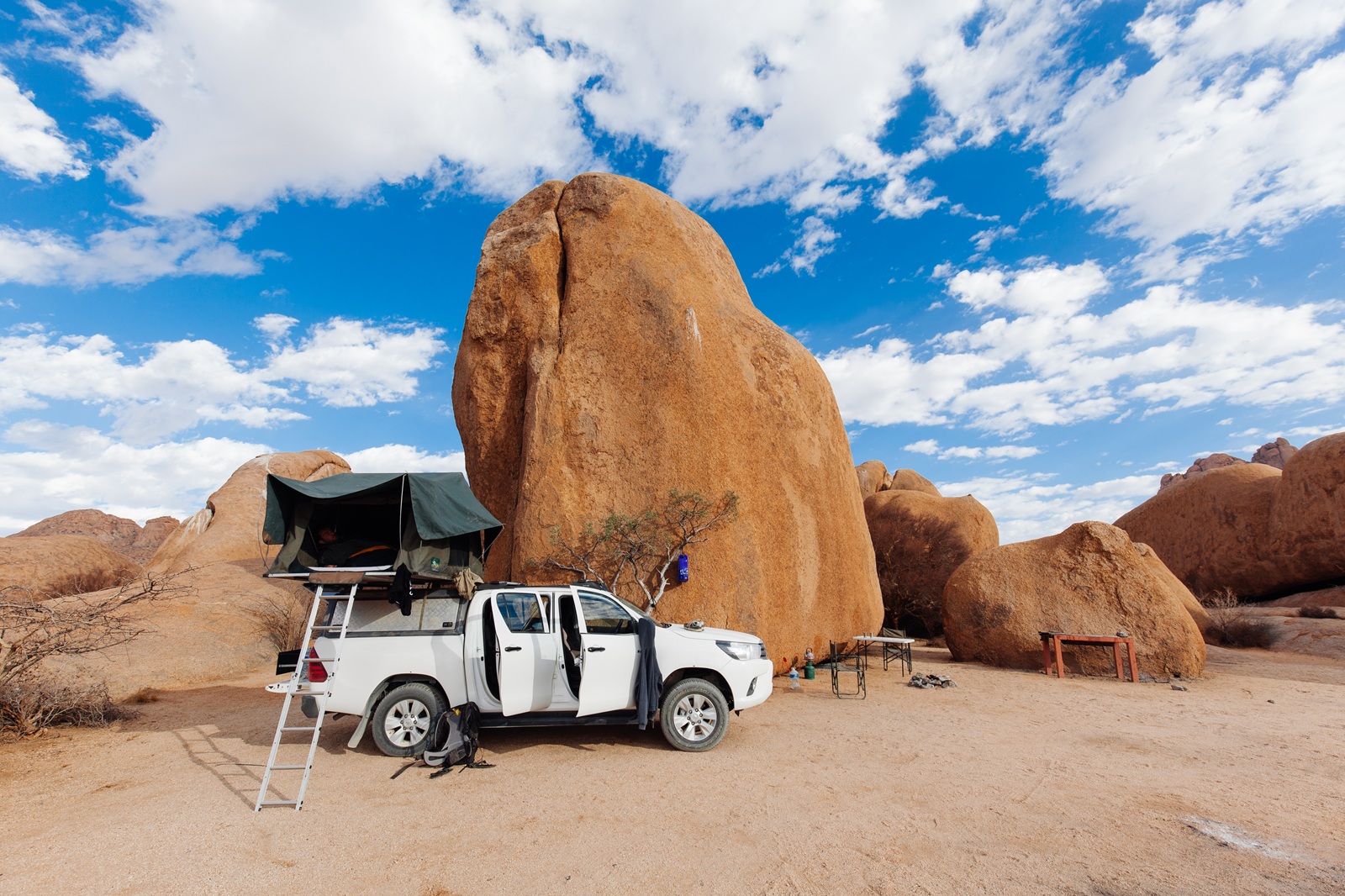 Safari Fahrzeug mit aufgebautem Dachzelt vor Steinmonolithen