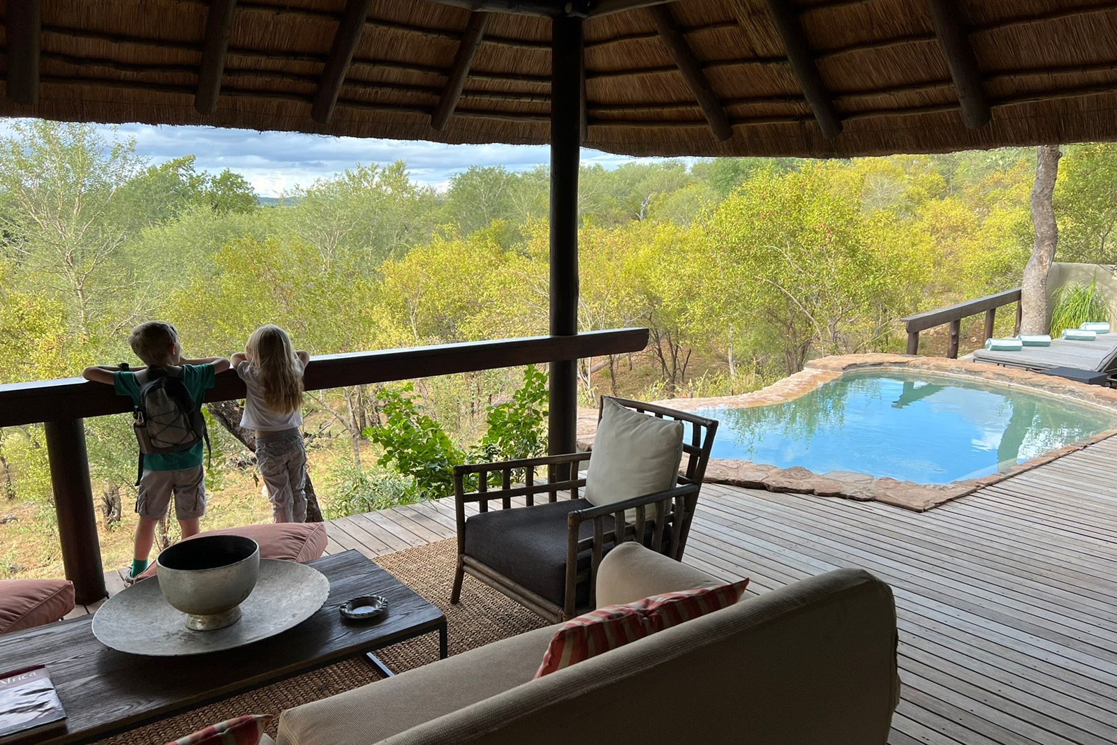 Zwei Kinder stehn auf der Terrasse einer Lodge mit privatem Pool und schauen in die Natur